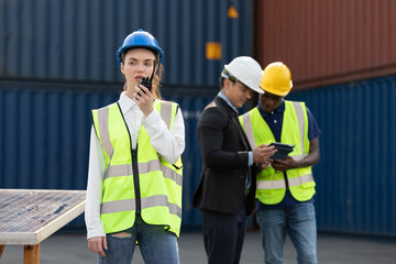 woman factory worker or engineer using walkie talkie for preparing a job in containers warehouse storage