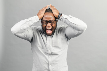 Mad frustrated black guy holding head and screams isolated on grey, angry African-American man with suffering face expression feels disappointment and depression, yelling with eyes closed