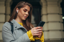 Woman using a smartphone and airpods outside