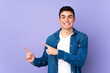 © luismolinero - Teenager caucasian  handsome man isolated on purple background frightened and pointing to the side