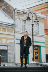 Wall Mural - Vertical shot of a Caucasian fashionable sexy man with a brown scarf on the street lamp background