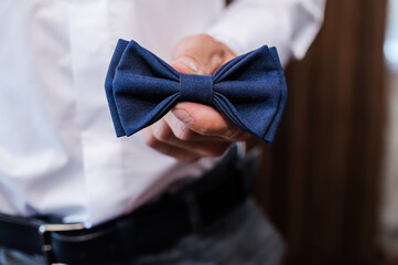 Wall Mural - Blue bow tie in the hands of the groom. Bow tie in the hands of a man