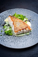 Wall Mural - Modern style traditional fried skrei cod fish filet with mashed potatoes and baby broccoli served as close-up on ceramic design plate with copy space