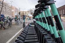 Selective Focus View, Row Of E-scooters With Eco Friendly Mobility Concept Of Sharing Electric Scooter, Park On Street In Front Of Train Station In Düsseldorf, Germany.