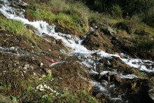 Natural View Of A Small Waterfall Flowing Downstream From A Hill