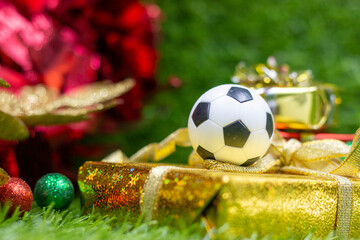 Wall Mural - Soccer Christmas Holiday with ball and Christmas decoration on green grass background
