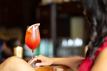 Wall Mural - Portrait of a black haired female sitting in the bar with a glass of cold cocktail