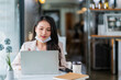 © whyframeshot - Asian attractive beautiful woman with face mask sitting at table near window at the cafe working using laptop while enjoying her coffee and dessert coffee break