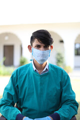 Canvas Print - Vertical shot of an Indian doctor with a medical uniform and mask on the clinic background