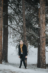 Wall Mural - Vertical shot of a caucasian stylish male posing outdoors in a snowy park