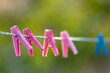 pink and blue clothespins hanging on a clothesline, focus on the second clothespin, shallow depth of field, close-up.