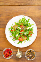 Sticker - Dish of arugula, tomatoes, dried meat and cheese. Salad on plate on wooden background