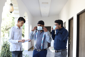 Poster - Closeup shot of three Indian men with masks on the clinic background