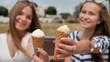 Two girls are presenting ice cream to the viewer.