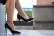 Woman's legs wearing stylish black high heel shoes in city