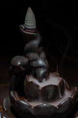 Ceramic backflow incense burner in the form of lotus flower. Incense cones holder. Dark mystic concept.