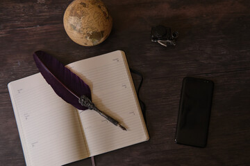 Wall Mural - Top view shot of a globe, notebook, inkwell, pen, and a cellphone on the wooden table