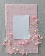 White Sheet Of Paper On A Background Of Pink Fabric, Decorated With Pink And White Artificial Roses And Beads