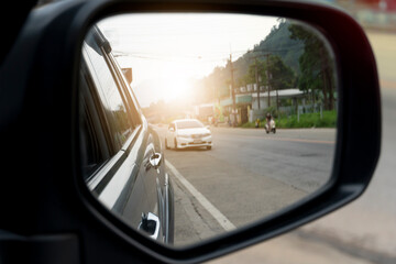 Wall Mural - Wing mirror view of dark gray car on the road heading towards the goal of the trip. with other cars in the back