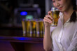 © Morakot - Beautiful Asian woman holding a glass of beer close up on background inside bar.