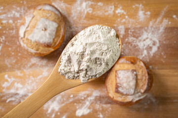 Italian bread blurred in background. Wooden spoon with wheat. Wooden base. Top view