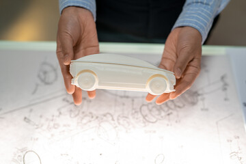 Poster - Holding model of car above sketch