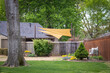 © Susan Vineyard  - Yard of fun house in early spring with Shade sails and privacy fence and harge trees - landscaping and outside seating.