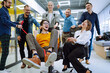 © maxbelchenko - Friendly work team  ride chairs in office room cheerfully excited diverse employees laugh while enjoying fun work break activities, creative friendly workers play a game together.