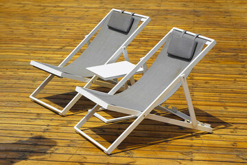 Two lounge chair on an exotic wood terrace. Two white summer chairs and a small table on the large open balcony terrace of the hotel room