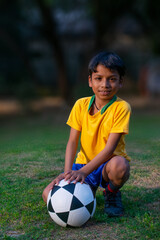 Wall Mural - Young boy Sitting in the ground with football 