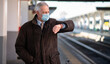 Masked businessman waiting for the train, covid and coronavirus mobility concept