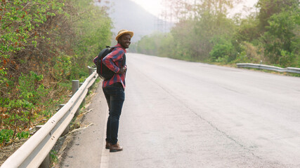 Wall Mural - African man traveler  walking on the highway road with backpack