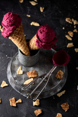 Poster - Vertical shot of two purple ice cream cones on a metal container surrounded by broken waffle pieces