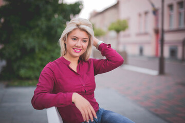 Wall Mural - Beautiful smiling Bosnian Caucasian woman sitting on a bench in a park