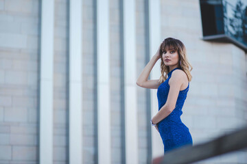 Poster - Shallow focus shot of a confident Caucasian female in a blue dress posing for the camera