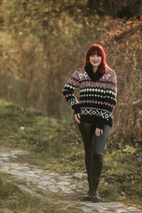 Poster - Vertical shot of a young smiling female with red hair posing in a warm sweater sit