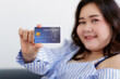 © Bangkok Click Studio - Close up shot of blue credit card use for shopping online transaction payment held by fingers of Asian young happy successful rich oversized businesswoman smiling look at camera in blurred background