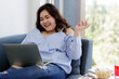 © Bangkok Click Studio - Asian young happy pretty sexy friendly fat woman sit relaxing laughing on blue fabric sofa have fun when talking chat and have conversation with friends via video call through laptop computer at home