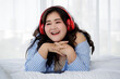 © Bangkok Click Studio - Asian young happy calm fat overweight woman lay down with happy smiling deep emotion peacefully while listening to music from big red earphones use playlist from black tablet at home in bedroom