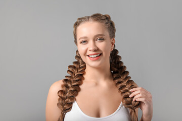 Canvas Print - Beautiful young woman with braided hair on grey background