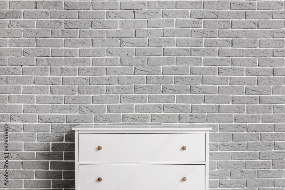 Modern chest of drawers on brick background