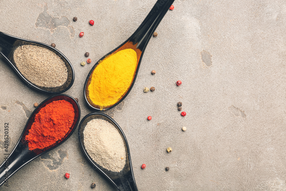 Spoons with different spices on grey background