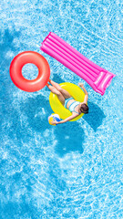 Wall Mural - Active young girl in swimming pool aerial top view from above, child relaxes and swims on inflatable ring donut and has fun in water on family vacation, tropical holiday resort
