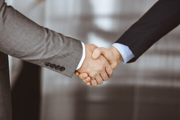 Business people in office suits standing and shaking hands, close-up. Business communication concept. Handshake and marketing