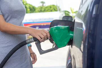 Blue car at gas station filled with fuel. Closeup pregnant woman hand pumping gasoline fuel in car at gas station.