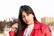 portrait of green eyed latina teenager in the park with red leather jacket