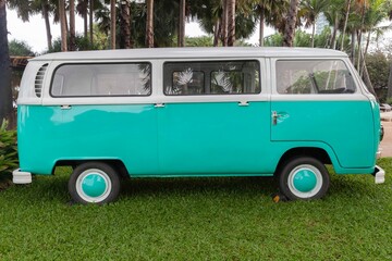 An old green vintage van parked with a large green garden in a beautiful garden