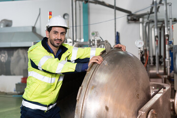 Wall Mural - Factory engineer and production machinery for food and medicine. A handsome young engineer inside a sterilizing chamber. Machine inspectors and maintenance.