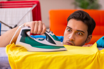 Young man husband doing ironing at home