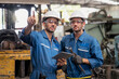 © Thirawatana - Mechanic holding a wrench and a tablet standing in front of an industrial forklift. Professional technicians are holding a tablet to control work in industrial plants.